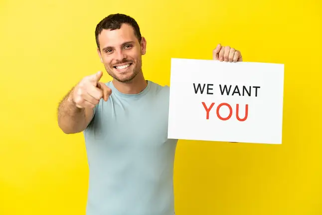 A person with a yellow background pointing and holding a banner.